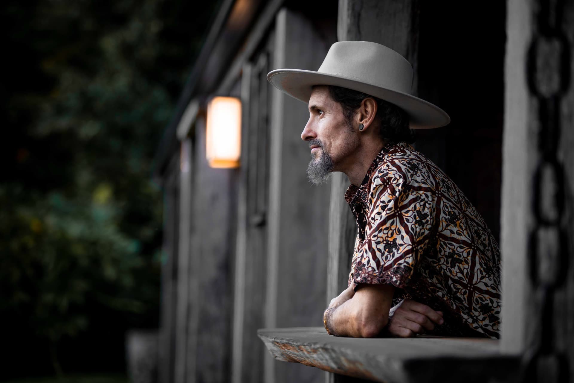 Murray Kyle in profile, leaning on a timber verandah rail at dusk